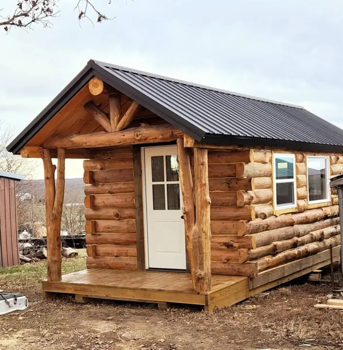 Small solid-log cabin with covered porch and metal roof