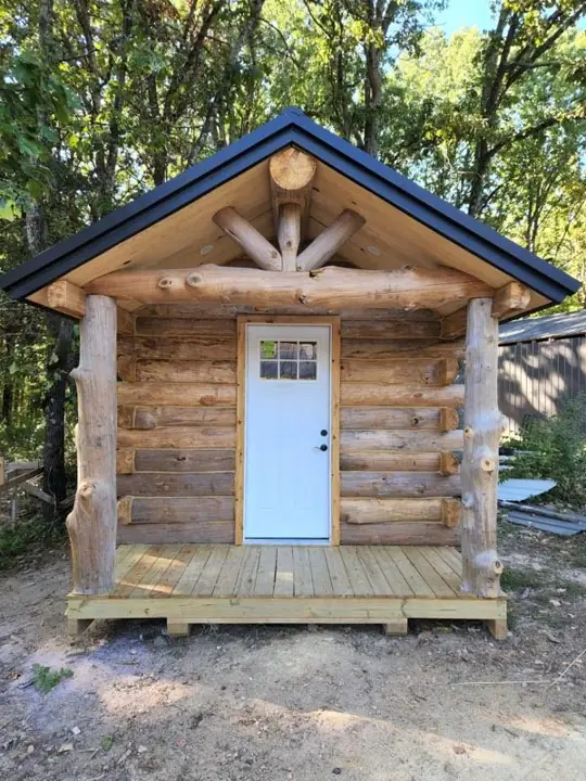 Small solid-log cabin front with gable trim and entry door