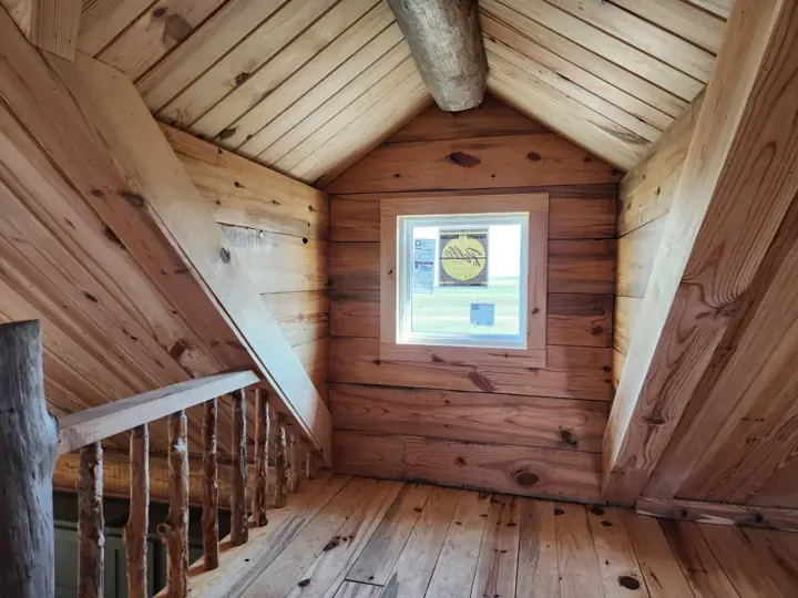 Loft railing and gable window under a wood ceiling