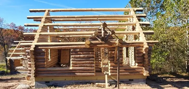 Log walls and roof framing going up on a large build